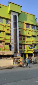 ein gelbes und grünes Gebäude mit Leuten, die davor laufen in der Unterkunft Tusthi Banquets in Kalkutta