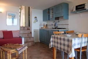 a kitchen with blue cabinets and a table with a red couch at Villino Elisa in Costa Paradiso
