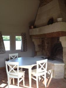 a dining room with a table and chairs and a fireplace at La Bouillerie du Clos in Branville