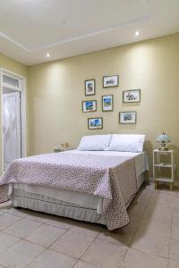 a bedroom with a large bed and some pictures on the wall at Vila Barroca Estalagem in São Cristóvão
