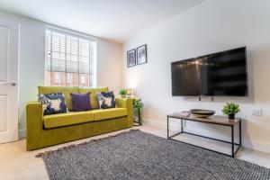 uma sala de estar com um sofá amarelo e uma televisão de ecrã plano em Saltbox Stays - Modern 3 Bed with off-street parking for 2 cars, fast Wifi, sleeps 6 em Ashby de la Zouch