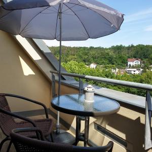 einen Tisch und Stühle auf einem Balkon mit Sonnenschirm in der Unterkunft Penzion a Restaurace Simanda in Prag