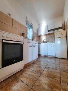 a large kitchen with white appliances and a tile floor at Apartman Marina in Selce
