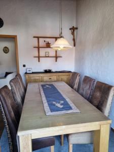 a dining room table with leather chairs and a light fixture at Burgauer Hof in Burgau