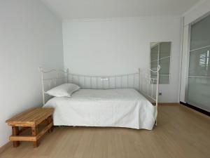 ein weißes Schlafzimmer mit einem Bett und einem Holztisch in der Unterkunft Casa Brisa del Este in Mala