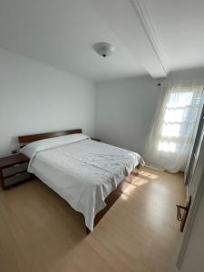 a white bedroom with a bed and a window at Casa Brisa del Este in Mala