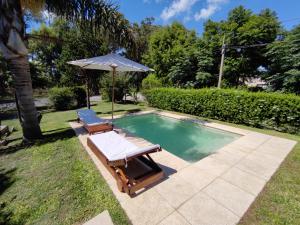 a swimming pool with an umbrella and a chair at Ybá Pitá in Colonia del Sacramento