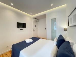 a bedroom with a large white bed and a tv at MyStay Porto Centro in Porto