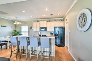 a kitchen with a black refrigerator and blue chairs at Pura Vida Crystal Beach House Walk to Beach! in Crystal Beach
