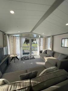 a living room with a couch and a television at Falconers Lodge with Hot Tub in Barmby on the Moor