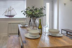 uma mesa de jantar com um vaso de flores e copos de vinho em The Swell, Rhosneigr - Ground floor 2 bed With Parking em Rhosneigr