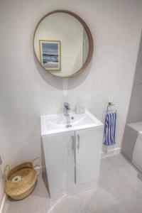 a white bathroom with a sink and a mirror at The Swell, Rhosneigr - Ground floor 2 bed With Parking in Rhosneigr