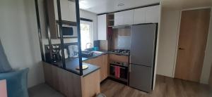 uma pequena cozinha com um frigorífico e um lavatório em Mobil-home de charme dans les Landes, neuf, tout équipé em Gastes