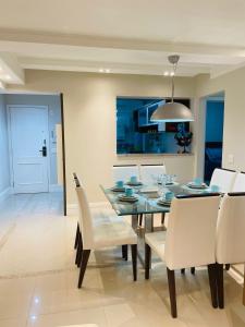 comedor con mesa de cristal y sillas blancas en Apartamento com 3 dormitórios en Balneário Camboriú