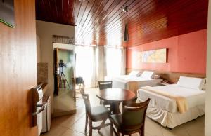 巴納內拉斯的住宿－Serra Golfe Apart Hotel，一间设有两张床和一张桌子及椅子的房间
