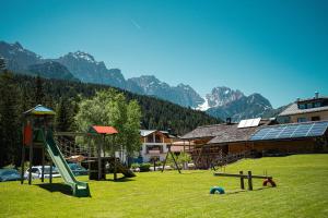 a playground with a slide in a field with mountains at MOIE' CAMERE in Padola