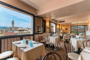 a dining room with tables and chairs and a large window at Hotel Pitti Palace al Ponte Vecchio in Florence