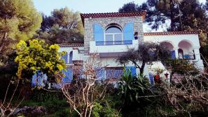 biały dom z niebieskimi oknami i drzewami w obiekcie Magnifique "Gite de la Garoupe" au Cap d'Antibes à 300m des plages w mieście Antibes