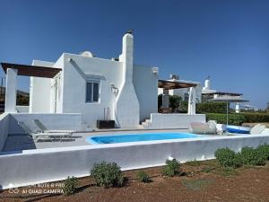 a villa with a swimming pool in front of a house at Sea Breeze Villas in Lachania