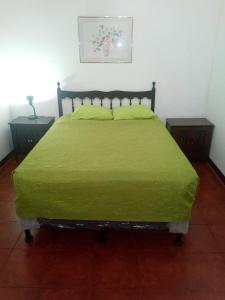 a bedroom with a bed with a green bedspread and two tables at Hotel Spring in Guatemala