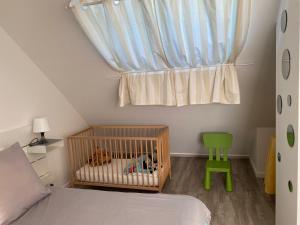 a bedroom with a crib and a window with a green chair at Logement calme et spacieux avec terrasses in Le Havre