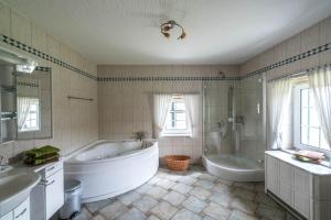 La grande salle de bains est pourvue d'une grande baignoire, d'un lavabo et d'une baignoire. dans l'établissement Jagdschloss Stift Ennenbach, à Ruppichteroth