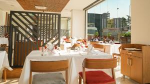 un restaurante con mesas y sillas blancas y ventanas en STAR LAND HOTEL BASTOS en Yaundé
