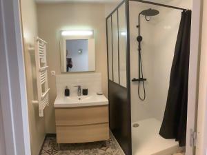 a bathroom with a sink and a shower with a mirror at Le filet Cherbourgeois in Cherbourg en Cotentin