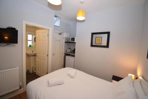 a small room with a white bed and a kitchen at Malton Central Apartments in Malton