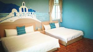 a bedroom with two beds and a painting on the wall at Camellia B&B in Taitung City