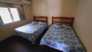 zwei Betten in einem kleinen Zimmer mit Fenster in der Unterkunft Solar Oliveira in Angra dos Reis + 15 Fotos