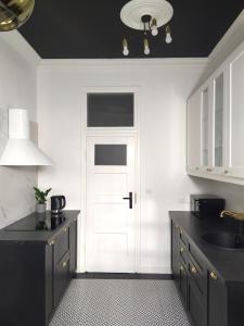 een keuken met zwarte werkbladen en een witte deur bij NDM Apartament in Warschau