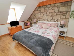 Un dormitorio con una cama y una pared de piedra. en 5 Swinton Mill Farm Cottage, en Coldstream