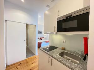 a kitchen with a sink and a room with a bed at MyStay Porto Centro in Porto