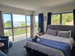 a bedroom with a bed with a view of the ocean at Tree House in Taieri Mouth