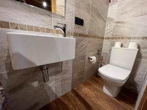 a bathroom with a white sink and a toilet at Casa rural LA TORRE recién rehabilitada. in Las Herrerías