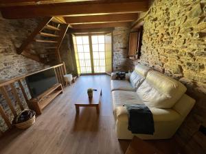 sala de estar con sofá y pared de piedra en Casa rural LA TORRE recién rehabilitada., en Las Herrerías