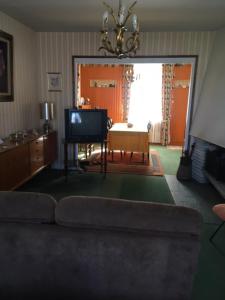 ein Wohnzimmer mit einem Sofa und einem TV in der Unterkunft Maison Proche de Barfleur accolée à un commerce in Anneville-en-Saire