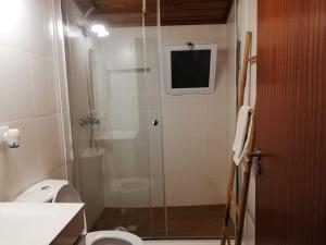 a bathroom with a shower with a toilet and a television at Casa Três Campos in Povoação