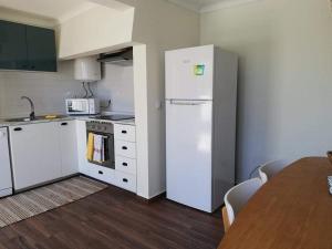 a kitchen with a white refrigerator and a table at Casa Três Campos, Povoação in Povoação +13 photos