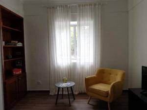 a living room with a chair and a table and a window at Casa Três Campos, Povoação in Povoação