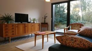 uma sala de estar com televisão numa cómoda de madeira em Gite spacieux et cosy à la campagne proche de Strasbourg em Achenheim
