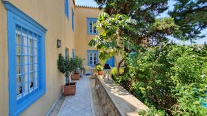 a building with a blue window and plants next to it at Palio Limani (Old Harbour) in Spetses