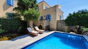 a swimming pool with two chairs and a house at Palio Limani (Old Harbour) in Spetses