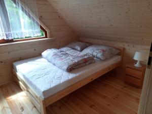 a bed in a log cabin with a window at Domki nad Stawem w Rynie in Ryn