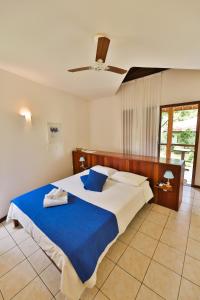 a bedroom with a large bed with blue sheets and a ceiling at Brasil Tropical Village in Pipa