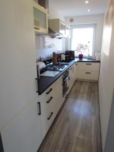 a kitchen with white cabinets and a wooden floor at Apartament Ella in Polanica-Zdrój
