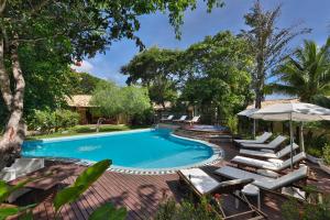 a swimming pool with lounge chairs and an umbrella at Brasil Tropical Village in Pipa