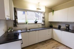 een keuken met witte kasten en zwarte aanrechtbladen bij Gezellige woning met 3 slaapkamers en gratis parking in Deinze