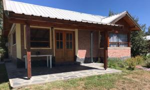 mały ceglany dom z drewnianymi drzwiami w obiekcie Casa Peral w mieście El Bolsón